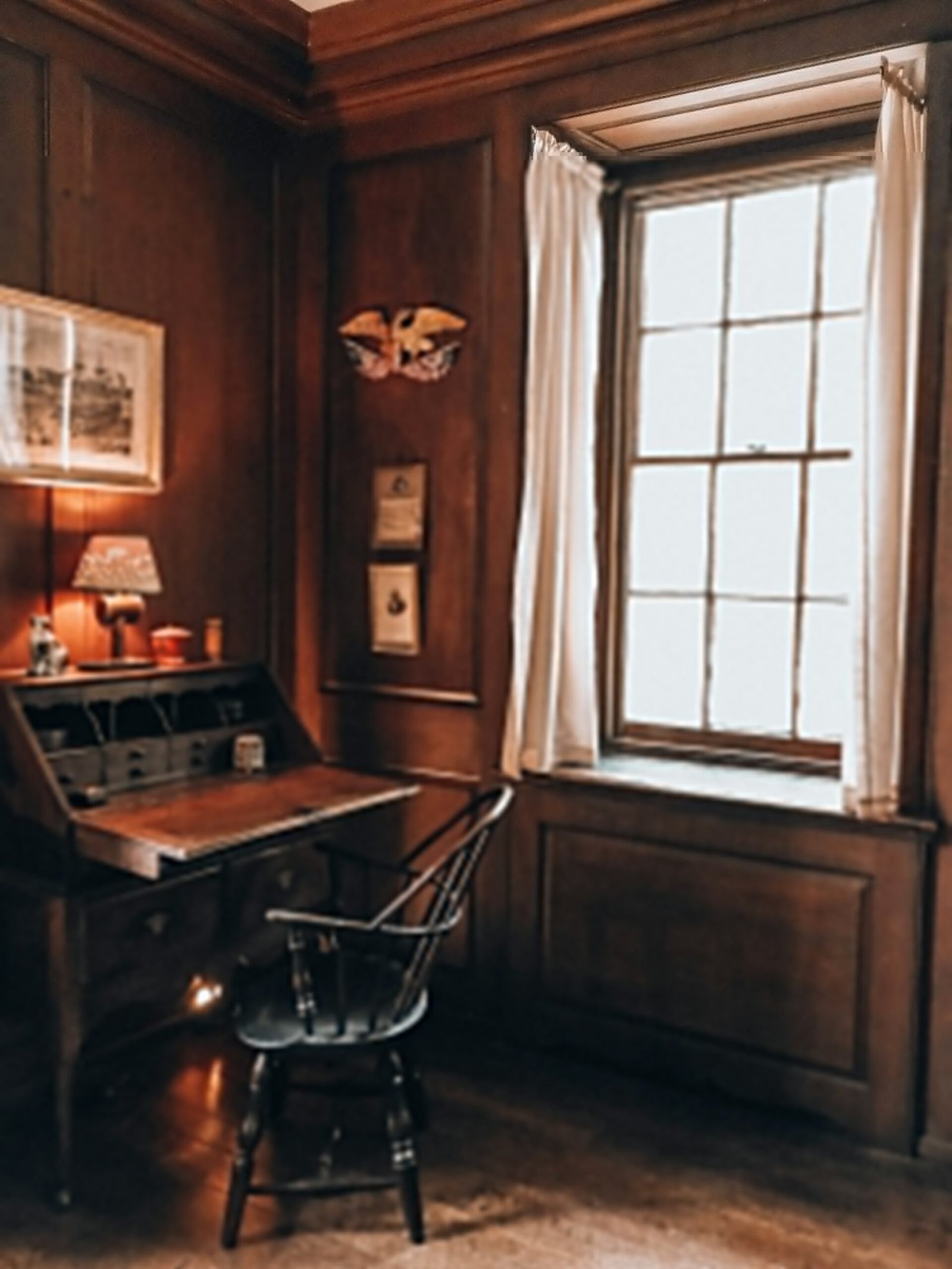 A wood-panelled study with an antique writing desk by a window